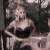 a woman in a black corset is standing next to another woman in a black dress .