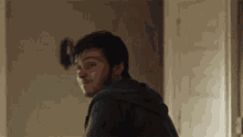 a young man is standing in a room with a door in the background .