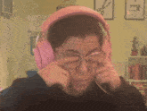 a person wearing pink headphones covering their ears