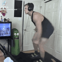 a man wearing headphones is doing squats in front of a rick and morty stuffed figure