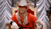 a man wearing a cowboy hat and a bandana is sitting in a chair .