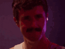 a man with a mustache is standing in front of a pink background