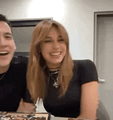 a man and a woman are sitting at a table and laughing .