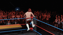 a wrestler is doing a handstand in a ring with a crowd watching