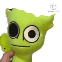 a person is holding a green stuffed animal that says kinemaster