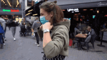 a woman wearing a face mask stands in front of a elmo pub