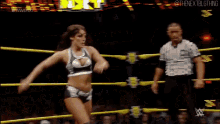 two women are wrestling in a wrestling ring with a referee watching .