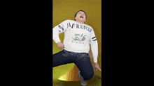 a man in a white sweater is kneeling down on the floor .