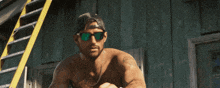 a shirtless man wearing sunglasses stands in front of a wooden building