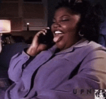 a woman is sitting on a couch talking on a cell phone .