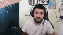 a man wearing headphones is sitting in front of a sign that says % 10 music