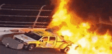 a yellow truck is on fire while driving down a road .