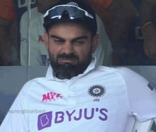 a man with a beard wearing a byju 's shirt makes a funny face