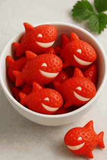 a white bowl filled with red fish shaped strawberries