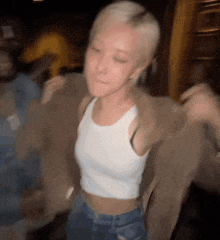 a woman in a white tank top and jeans is dancing in a crowded room .
