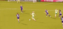 a soccer game is being played in front of a large coca cola sign