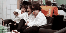 a group of young men are sitting on a couch taking a selfie with their cell phones .