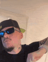 a man wearing sunglasses and a hat has a tattoo on his arm that says u.