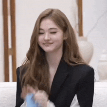 a woman in a black jacket is sitting on a couch .