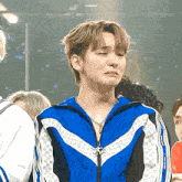 a young man in a blue jacket is crying while sitting in a crowd of people .