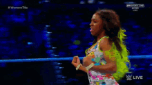 a woman in a colorful outfit is standing in a wrestling ring on a sports channel