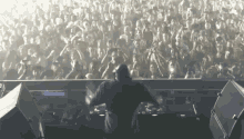 a dj playing music in front of a crowd with their hands in the air