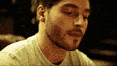 a close up of a man 's face with a beard wearing a white shirt