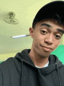 a young man wearing a black hat and a black hoodie poses for a picture