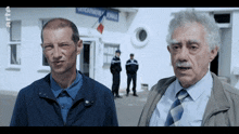 two men are standing in front of a building with a sign that says gendarmerie nationale