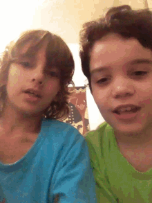 two young boys in blue and green shirts are posing for a picture