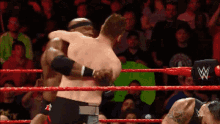 two wrestlers are hugging in a wrestling ring with a w on the side