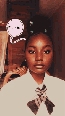 a girl in a plaid shirt and tie has a pink balloon on her forehead