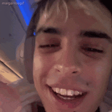 a young man wearing headphones is smiling and making a face with his hand .