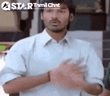 a man in a white shirt is standing in front of a star tamil chat sign