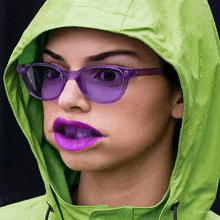 a woman wearing purple sunglasses and a green jacket has her mouth open