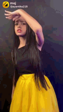 a girl wearing a yellow skirt and a black top with the name moj on the bottom right