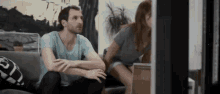 a man and woman are sitting on a couch looking at a laptop computer .