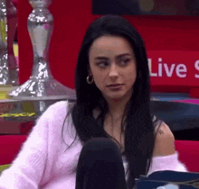 a woman is sitting in front of a red sign that says live