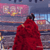 a woman in a red dress stands in front of a large screen that says " est "