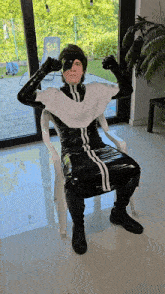 a man in a black and white outfit is sitting in a white chair