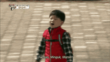 a young boy in a red vest is saying daehan minguk manse