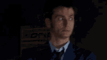 a man in a suit and tie is making a surprised face in front of a sign that says one .
