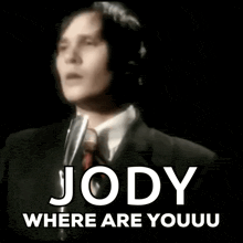 a man in a suit and tie is singing into a microphone with the words jody where are you u on the bottom .