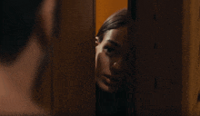 a woman peeking out from behind a door with a man behind her