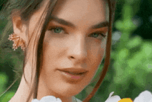 a close up of a woman 's face with a flower in her hand .