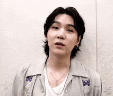 a close up of a young man wearing a necklace and earrings .
