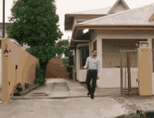 a man is walking down a sidewalk in front of a house with the number 63a