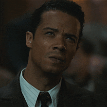 a man wearing a suit and tie looks at the camera