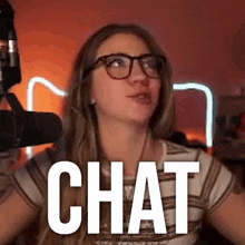 a woman wearing glasses is standing in front of a microphone and the word chat is on the screen .