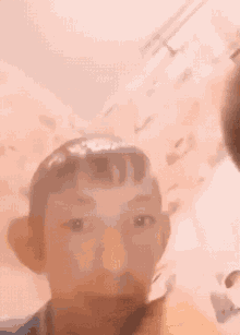 a close up of a person 's face with a pink wall behind them